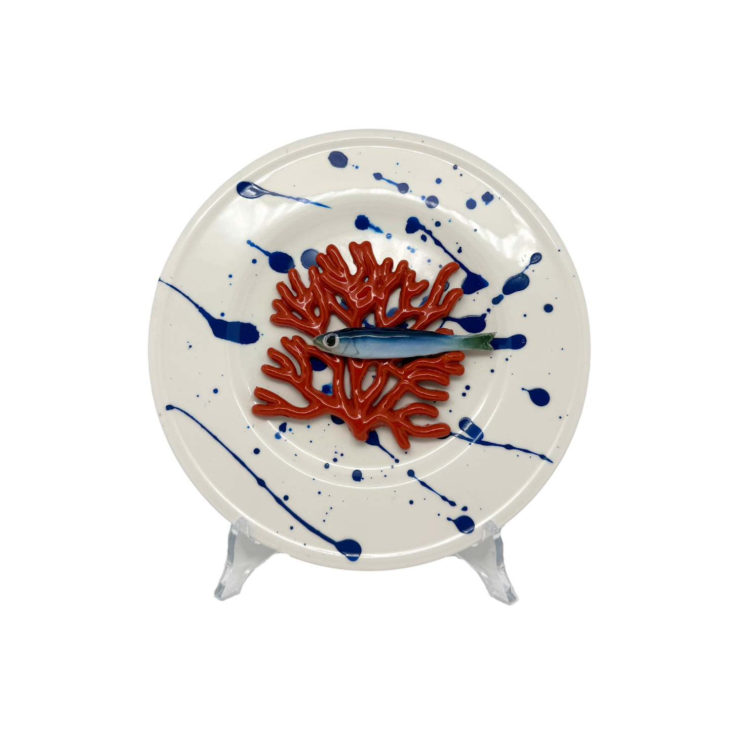 Koraal piccolo met sardientje op wit bord met blauwe verfspetters, 21 cm rond.