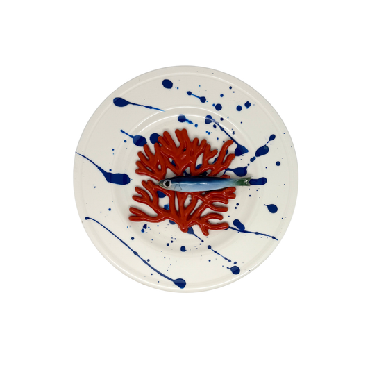 Koraal piccolo met sardientje op wit bord met blauwe verfspetters, 21 cm rond.